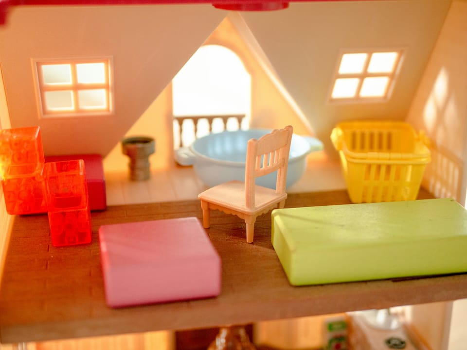 Second floor of a doll house, with a chair and other objects.